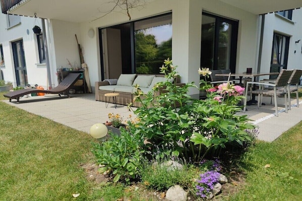 A modern outdoor patio with a sofa, chairs, and a dining table. - Holiday apartment WH (Garmisch-Partenkirchen)