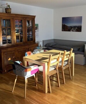 A dining area with a wooden table and chairs, a cabinet with glass doors, and a painting on the wall. - Holiday apartment WH (Garmisch-Partenkirchen)