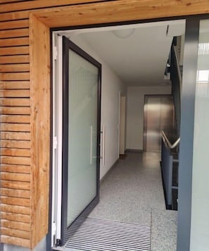 A hallway with a sliding glass door, a metal staircase, and a tiled floor. - Holiday apartment WH (Garmisch-Partenkirchen)