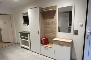 A room with a wardrobe, a shelf unit, and a mirror.