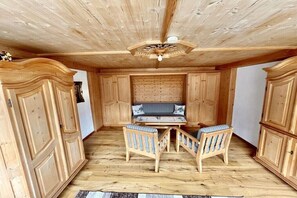 Ein Zimmer mit Holzboden, einer zentralen Sitzecke mit Tisch und Stühlen sowie Holzschränken.