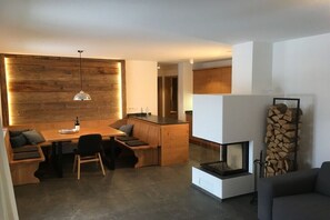 Eine moderne Küche mit Holzschränken, einem Essbereich mit einer Bank und einem Kamin.