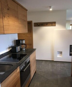 Eine moderne Küche mit Holzausstattung, einer schwarzen Arbeitsplatte, einer Kaffeemaschine und einem eingebauten Backofen.
