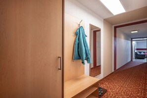 Ein Flur mit einem Holzschrank, einer Bank und einem Kleiderständer mit einer blauen Jacke.