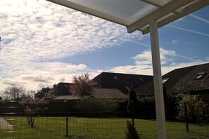 Ein Wohngebiet mit einer überdachten Terrasse, einem eingezäunten Garten und Häusern im Hintergrund.