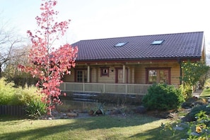 Ein zweistöckiges Haus mit Veranda, einer kleinen Terrasse und einem eingezäunten Garten.