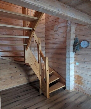 Eine Holztreppe mit Handlauf, einer Wanduhr und einer Kiefernzapfen-Dekoration.