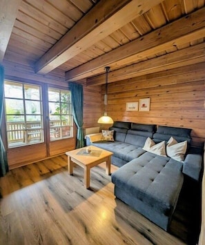 Ein gemütlicher Raum mit Holzwänden, einem blauen Sofa, einem Holztisch und einer Hängelampe.