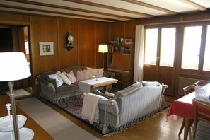 A traditional room with wooden paneling, a sofa, a table, and a bookshelf.