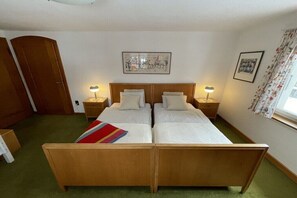 A double bed with two bedside tables, a wooden wardrobe, and a framed picture on the wall.