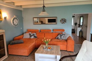 Ein Wohnzimmer mit einer Eckcouch, einem Couchtisch und einer Wanduhr.