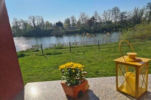 Ein Balkon mit Seeblick, einem Blumentopf und einer Laterne.