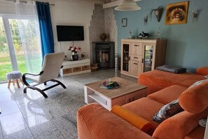Ein Wohnzimmer mit einer Couch, einem Sessel, einem Couchtisch, einem Kamin und einem Fernseher.