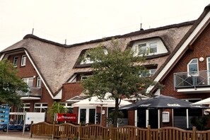 Ein Gebäude mit einem Strohdach, einem Schild mit der Aufschrift 'La Primavera' und Außenplätzen mit Sonnenschirmen.