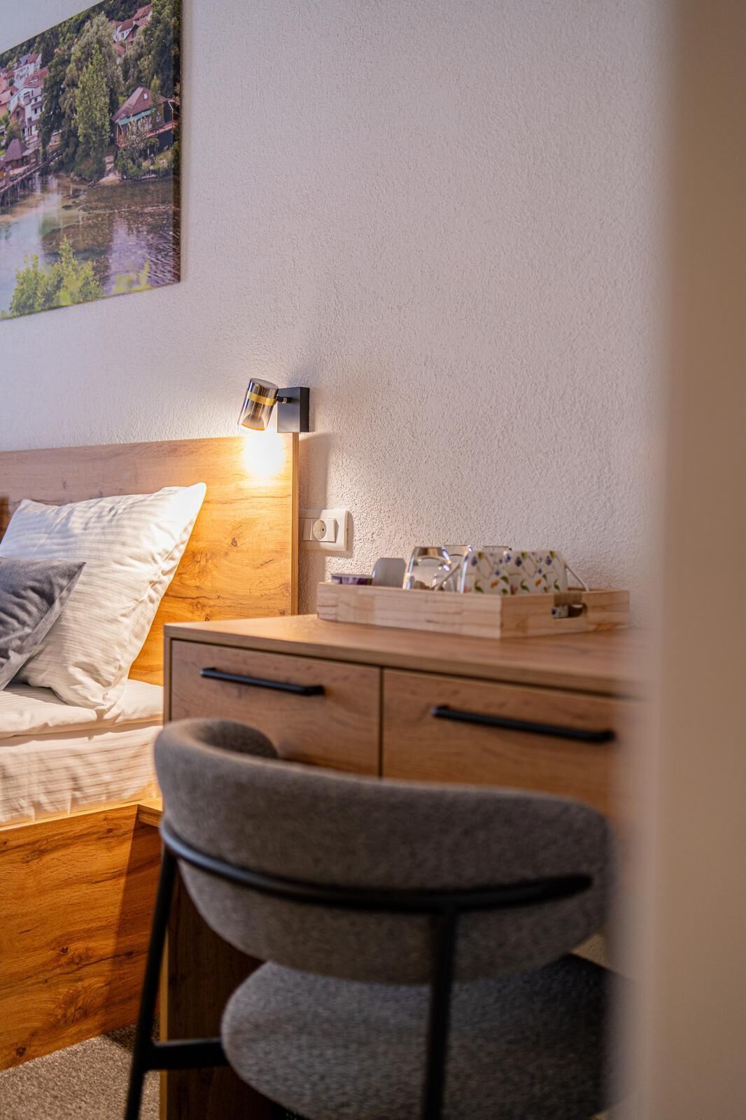 Ein Schlafzimmer mit Bett, Nachttisch, Lampe und einem Sessel.