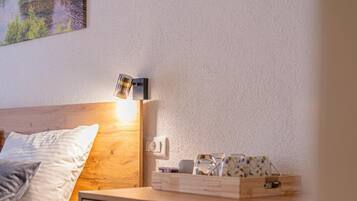 Ein Schlafzimmer mit Bett, Nachttisch, Lampe und einem Sessel.
