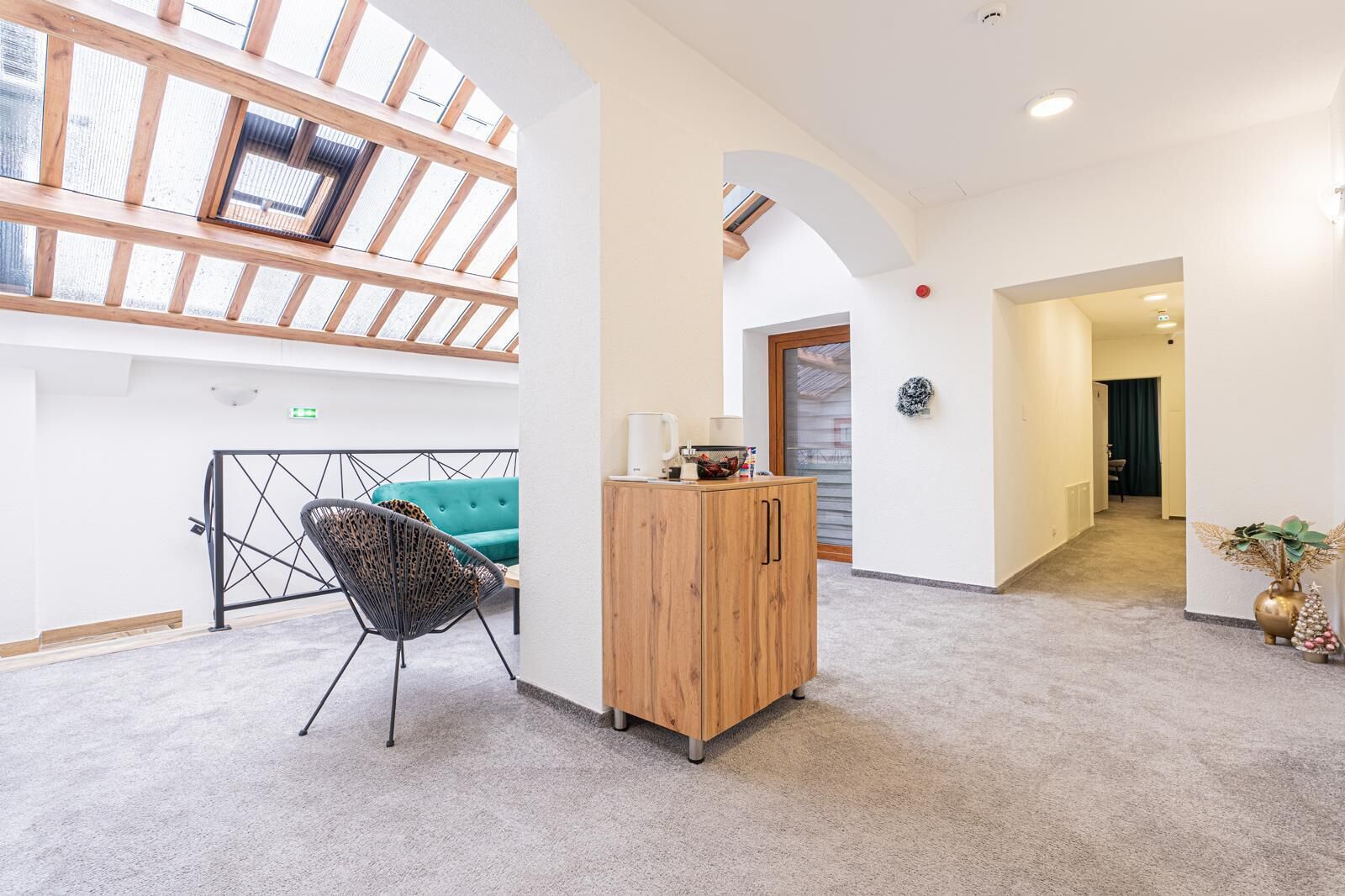 Un ambiente spazioso con soffitto alto, un mobile in legno, un divano verde e una poltrona.