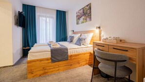 A bedroom with a bed, a desk, a chair, and a painting on the wall. - Hotel Una (Sarajevo)