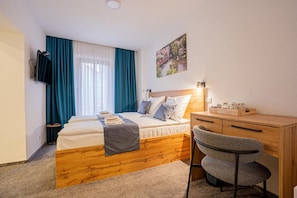 Ein Hotelzimmer mit einem Bett, einem Schreibtisch, einem Stuhl, einem Fernseher und einem Bild an der Wand.