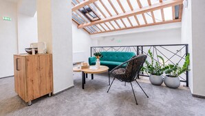 A modern interior with a wooden cabinet, a teal sofa, a wicker chair, and potted plants. - Hotel Una (Sarajevo)