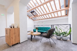 Ein modernes Interieur mit einem Holzschrank, einem grünen Sofa, einem Korbstuhl und Blumentöpfen.