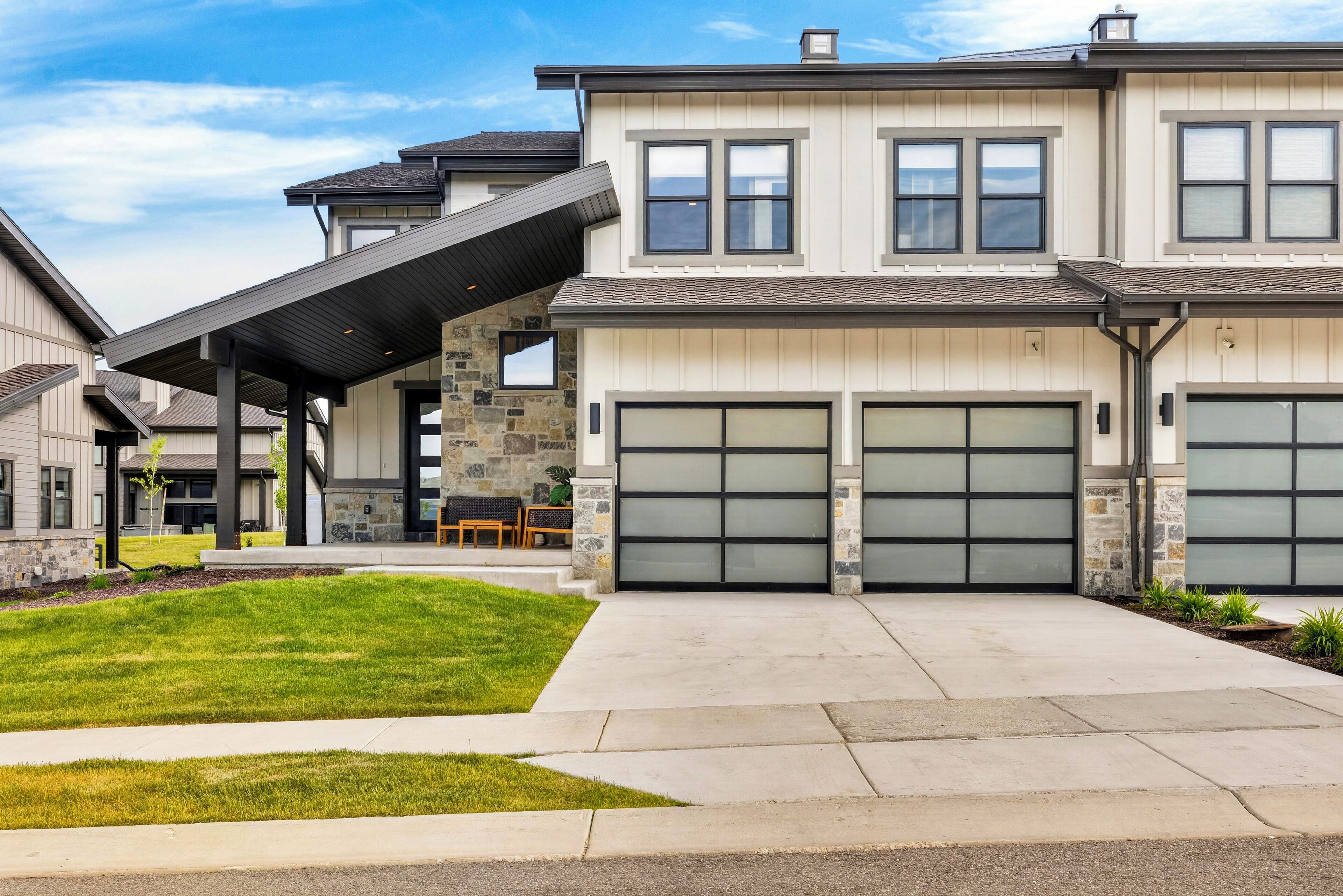 A two-story house with a garage, a covered patio, and a stone exterior.