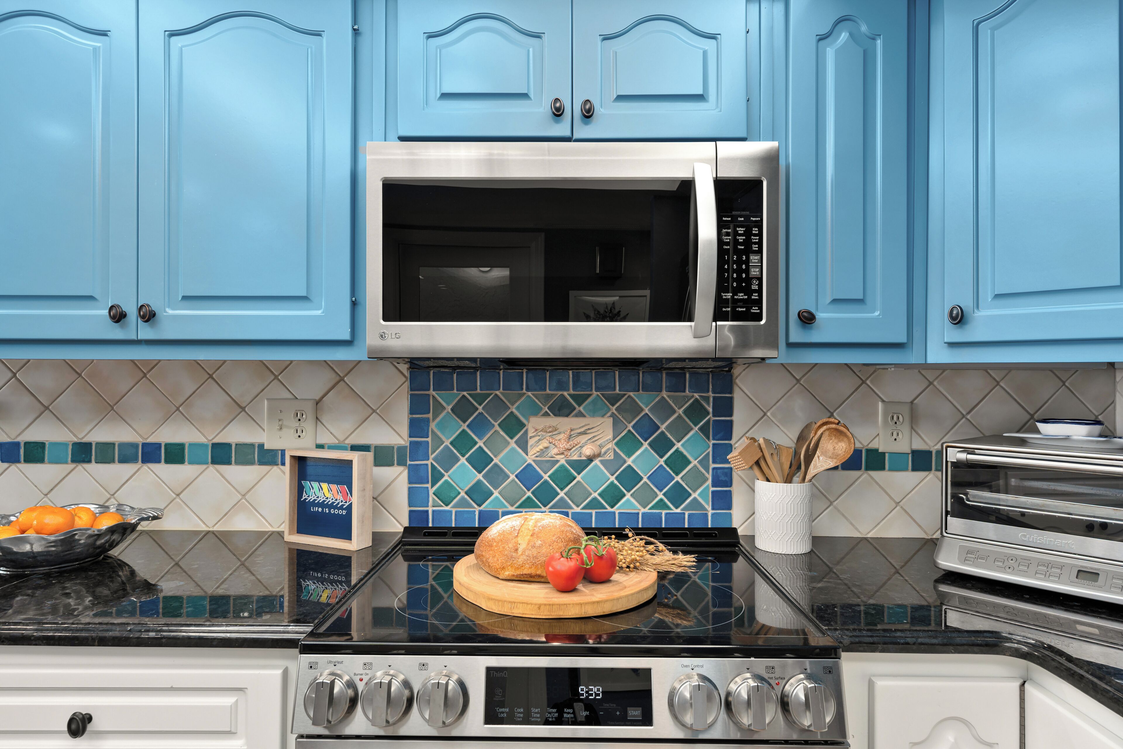 A kitchen with blue cabinets, a microwave, a stove, and a toaster.