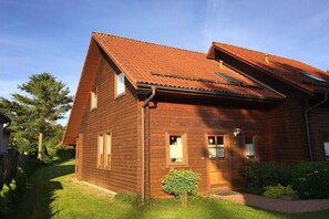 Ein Holzhaus mit geneigtem Dach, einer kleinen Veranda und einem gepflegten Rasen.