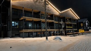 Een meerlaags gebouw met balkons, een trap en sneeuw op de grond.