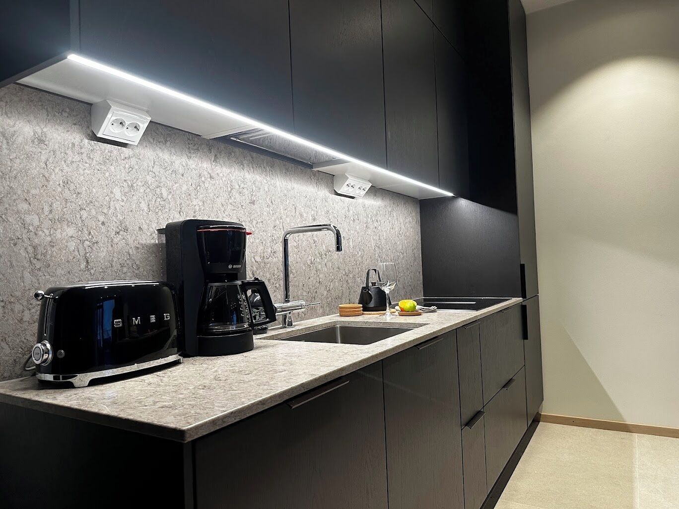 A modern kitchen with a built-in coffee maker, a sink, and a countertop.