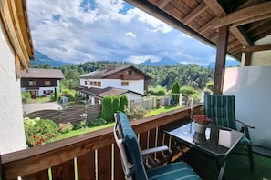 Ein Balkon mit Tisch und Stühlen, mit Blick auf eine Wohngegend mit Häusern und Bergen.