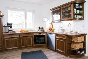 Eine Küche mit Holzausstattung, einem Backofen, einem Geschirrspüler und einem Fenster.