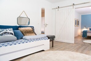 Ein modernes Schlafzimmer mit einem Bett, einem kleinen Hocker, einem weißen Kleiderschrank und einem Spiegel an der Wand.