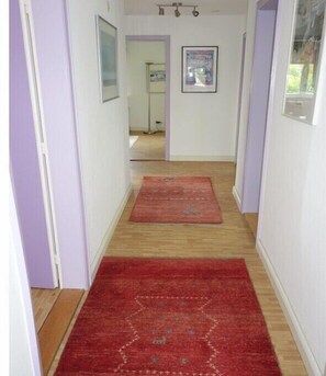 A hallway with a red carpet, white walls, and a door at the end. - "Seagull under thatch" (Nebel)