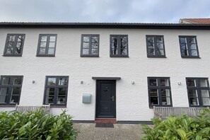 Ein weißes Gebäude mit schwarzem Eingang und Fenstern.