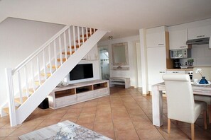 Ein moderner Wohnraum mit Treppe, Essbereich und Küche.