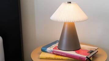 Abajur com cúpula franzida sobre uma pequena mesa com livros.