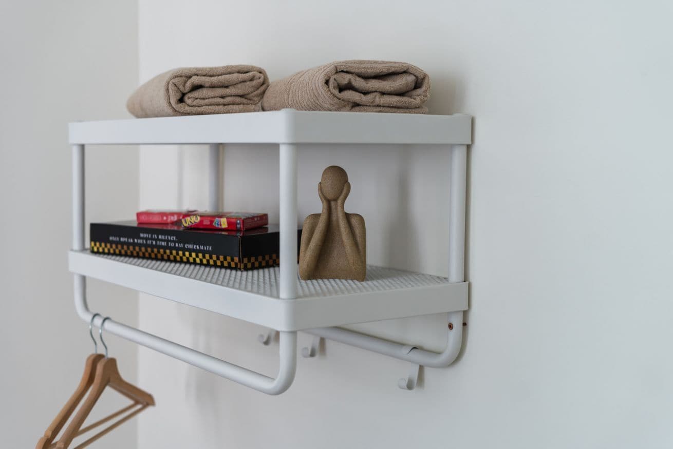 Un estante blanco con toallas, un libro y un objeto decorativo.