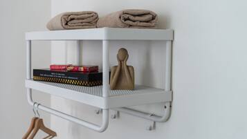 Un estante blanco con toallas, un libro y un objeto decorativo.