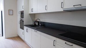 Une cuisine avec des armoires blanches, un comptoir noir et une hotte de cuisinière en acier inoxydable.