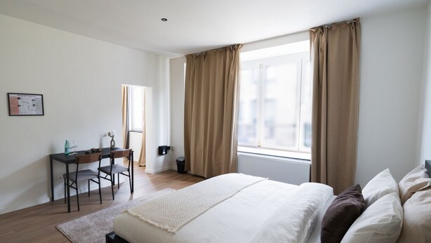 Une chambre à coucher avec un lit, un bureau et une fenêtre avec des rideaux.