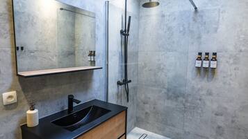 Un bagno moderno con doppio lavandino, un ampio specchio, cabina doccia in vetro e uno scaffale con articoli da toilette.