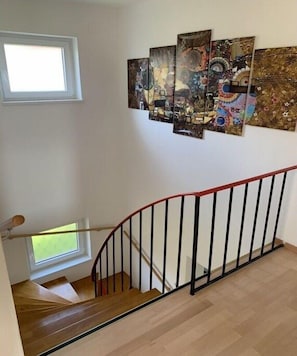 A staircase with a red handrail, wooden steps, and a window at the top.