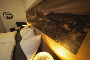 A room with a bed, a chair, a wall-mounted painting, and a sign with a deer and the word 'Servus.' - Holiday apartment in Lofer with swimming pool (Lofer)