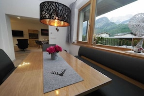 A modern dining area with a wooden table, black chairs, a bench, and a decorative vase with flowers. - Holiday apartment in Lofer with swimming pool (Lofer)