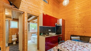 Ein Holzhütten-Innenraum mit Küche, Essbereich und Badezimmer.