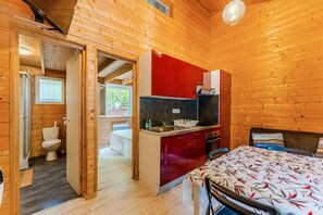 Ein Holzhütten-Innenraum mit Küche, Essbereich und Badezimmer.