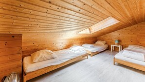 Eine Holzhütte mit geneigtem Dach und Holzwänden, ausgestattet mit zwei Betten mit wei ßen Leinen.