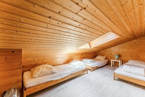 Eine Holzhütte mit geneigtem Dach und Holzwänden, ausgestattet mit zwei Betten mit weißen Leinen.