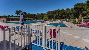 Ein Poolbereich mit mehreren Schwimmbecken, Liegestühlen und Sonnenschirmen.